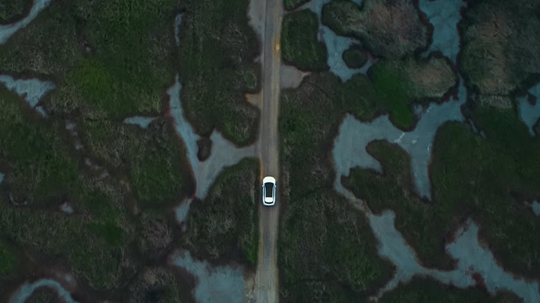 Kia EV6. Driving through landscape. Seen from above.